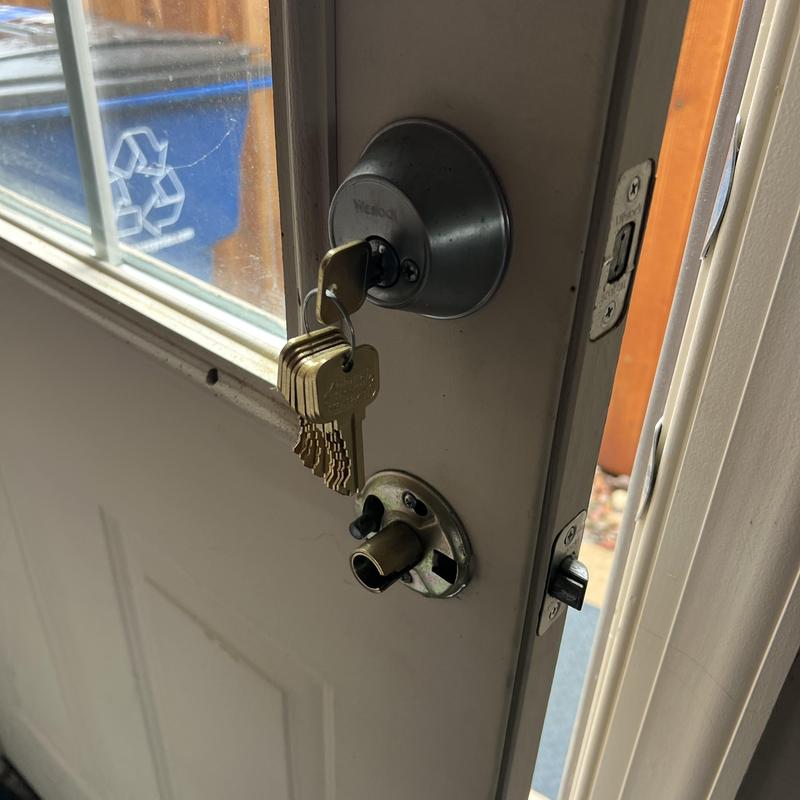 Door deadbolt lock with rekeyed keys hanging in cylinder