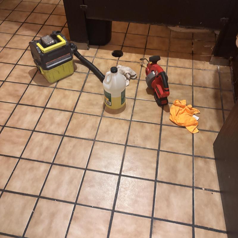 Floor drain with plumbing tools and cleaning supplies