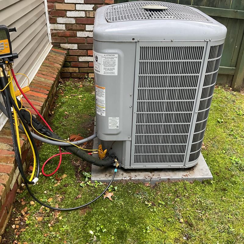 Condenser unit with attached HVAC gauges on grass Condenser unit with attached HVAC gauges on grass