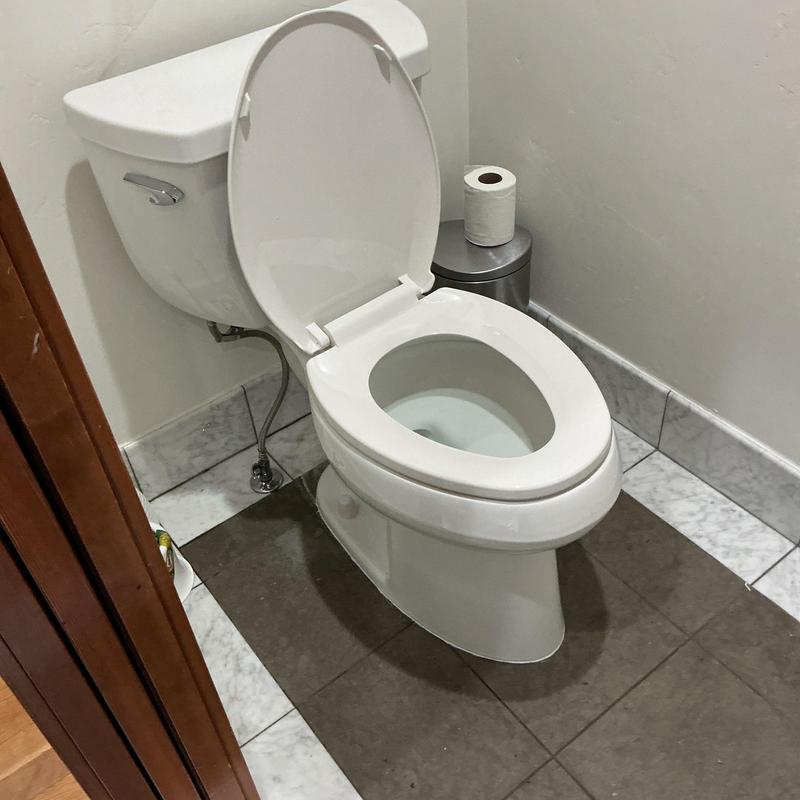 Pressure assist flush toilet installed in bathroom corner