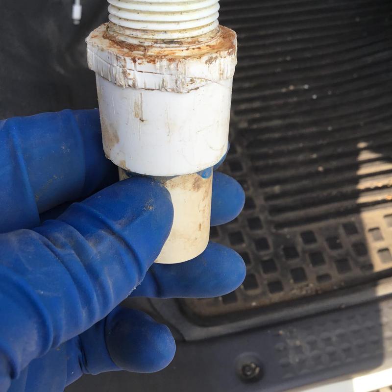PVC water service line fitting held by gloved hand