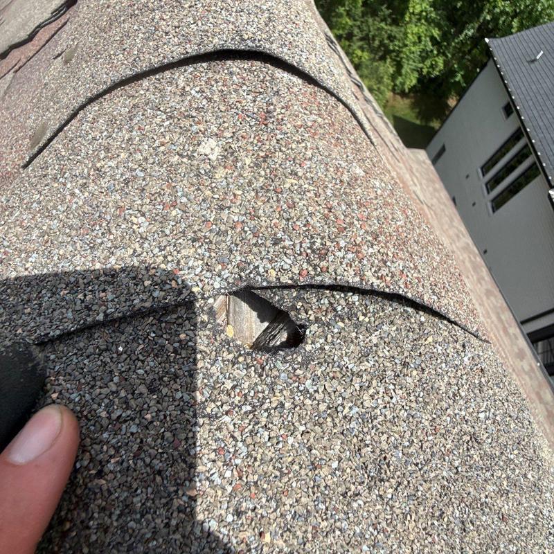 Asphalt shingle roof with puncture hole and damage