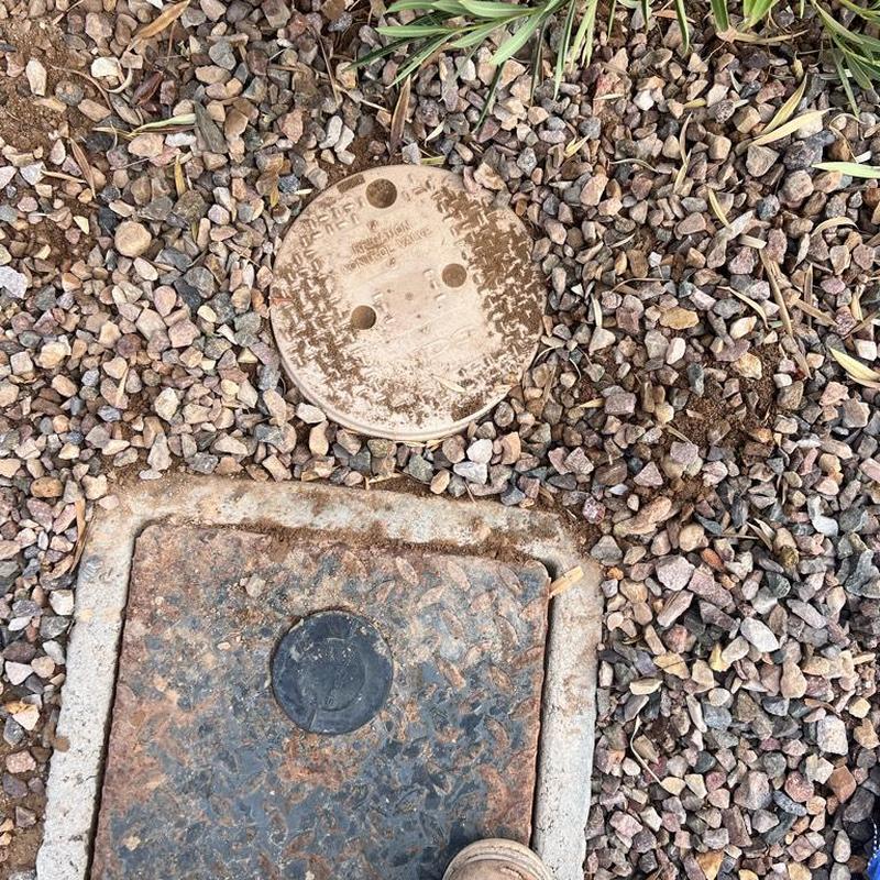 Water meter box and valve cover in gravel bed Water meter box and valve cover in gravel bed