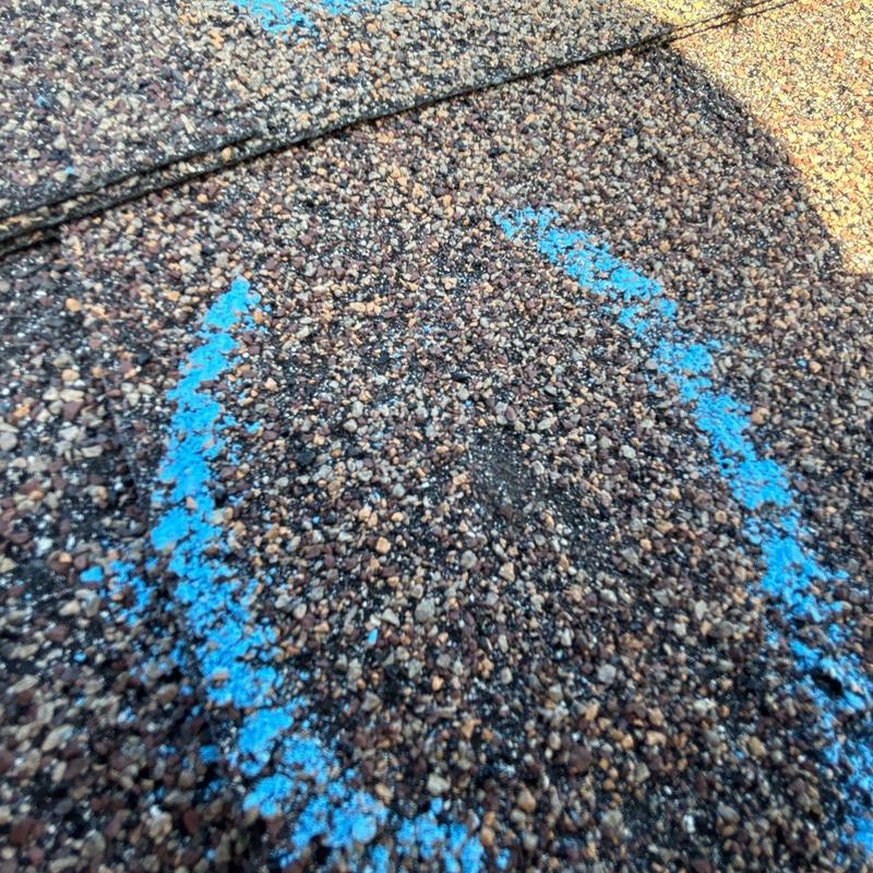 Asphalt shingle hail damage marked with blue circle