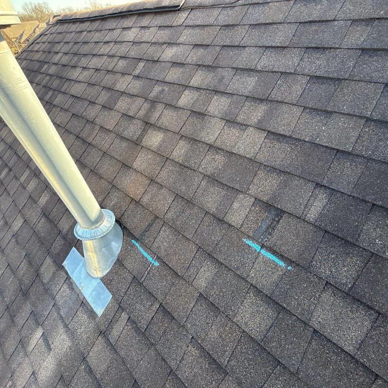 Asphalt roof shingles with hail damage marked in blue