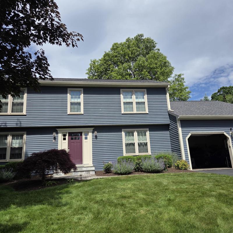 New asphalt shingle roof on blue two-story house New asphalt shingle roof on blue two-story house