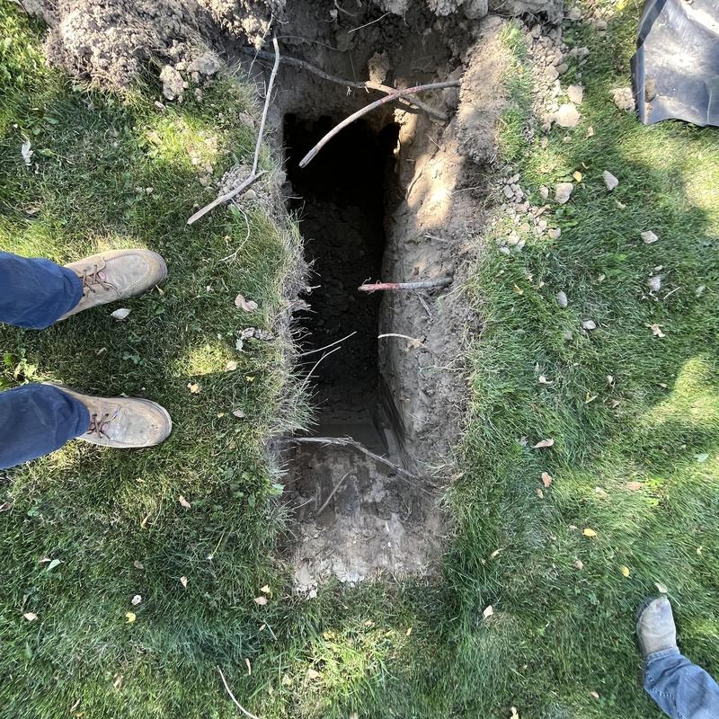 Septic tank test hole excavation in grassy yard
