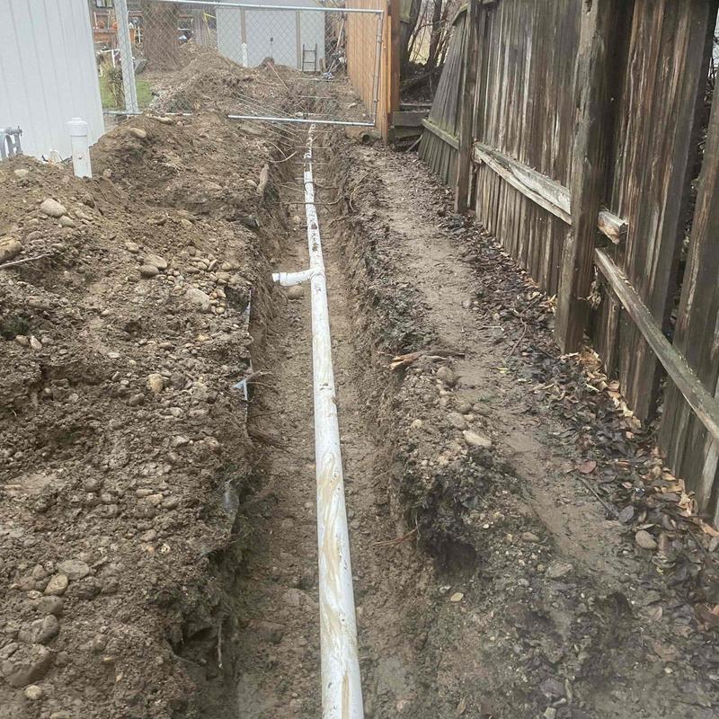PVC sewer line trench excavation beside driveway