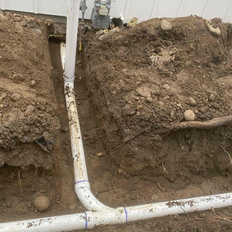 PVC drainage pipe installation in trench near house wall