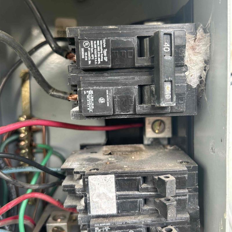 Electrical breaker panel with exposed wiring and dust buildup