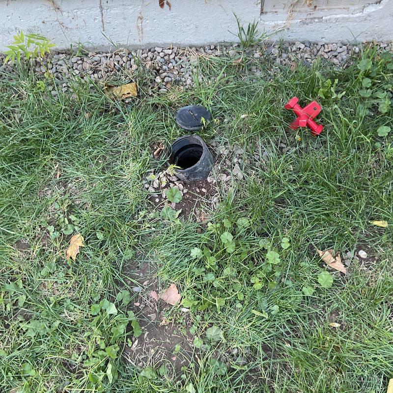 Main sewer cleanout with open cap in grassy yard