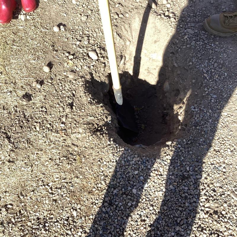 Sewer line excavation hole with shovel and gravel ground