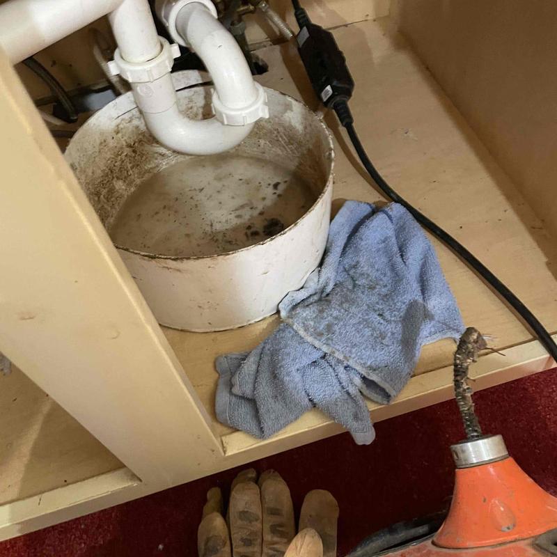 Kitchen sink drain with plumbing snake and bucket