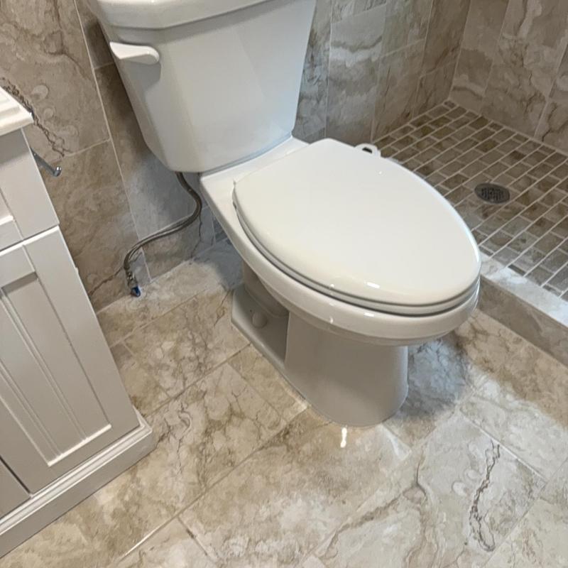Toilet with closed lid in tiled bathroom corner