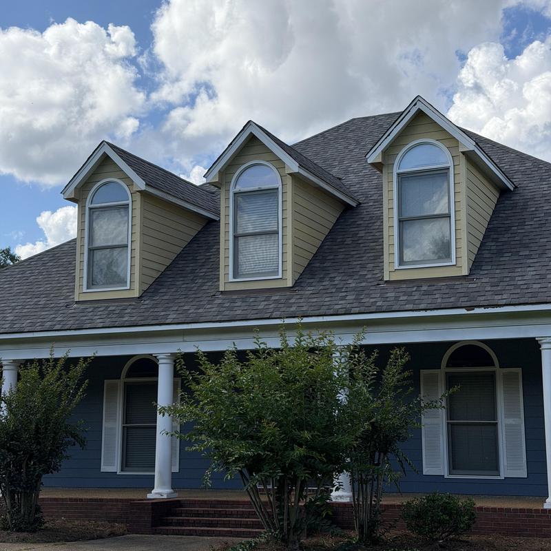Dormer siding on residential roof under cloudy sky