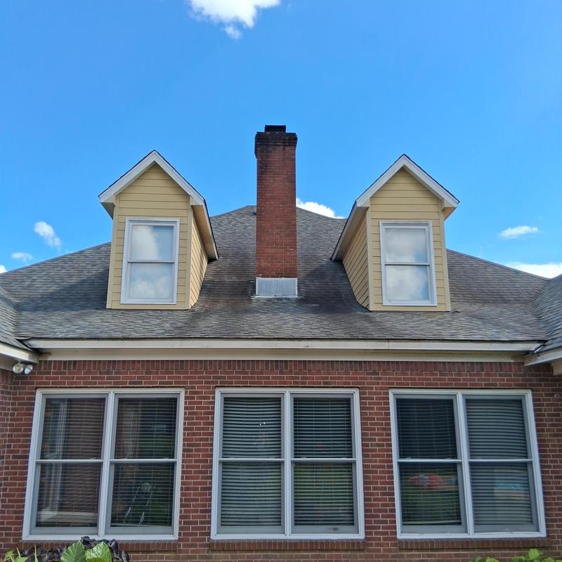 Siding soffit trim on dormer windows with chimney background