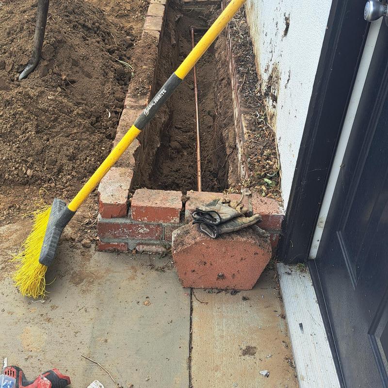 Copper water line exposed in backyard trench near slab
