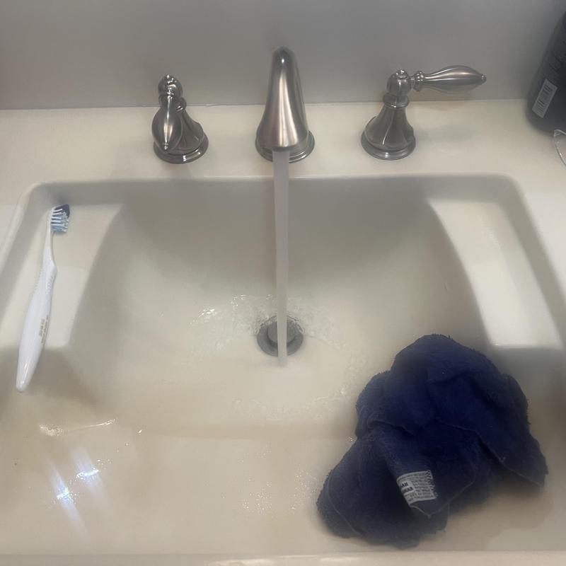 Bathroom sink with running water and cloth inside basin Bathroom sink with running water and cloth inside basin