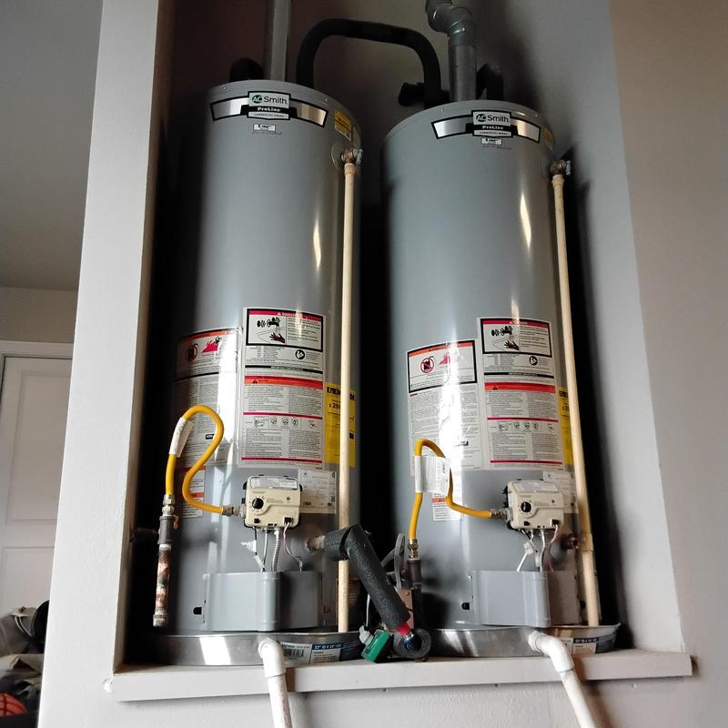 Tank water heaters side by side with piping and controls