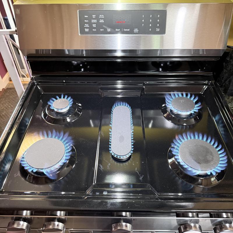 Gas stove burners with blue flames lit during LP conversion test