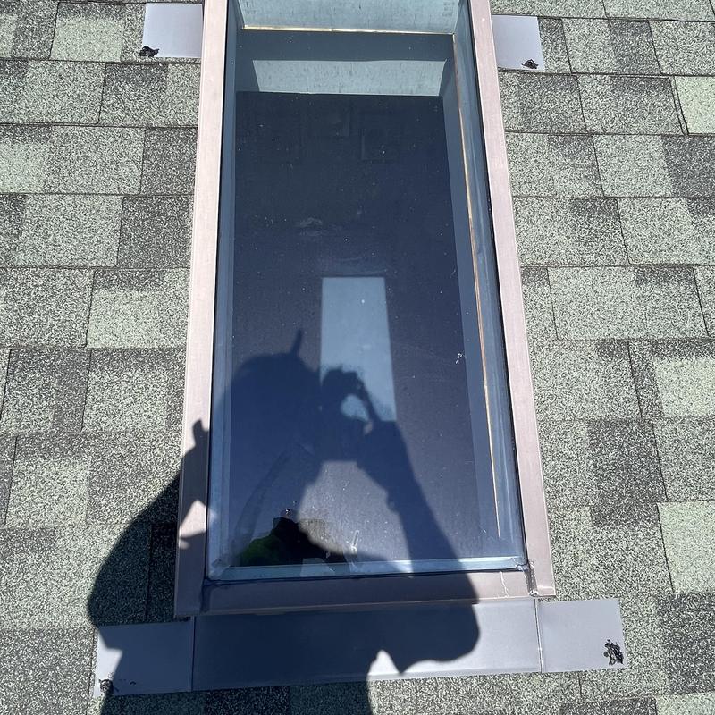 Skylight with surrounding roof shingles and flashing