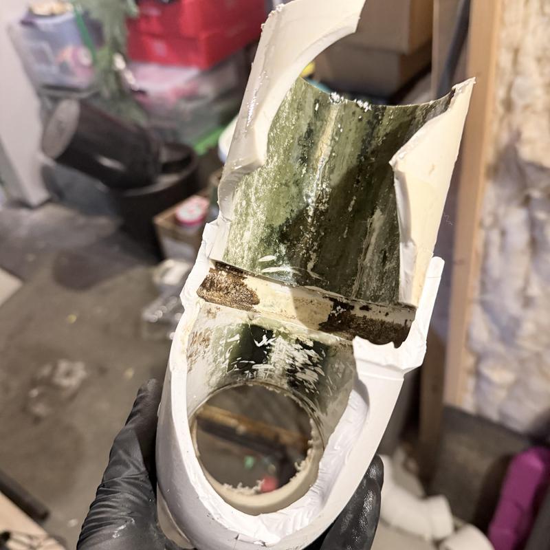 Cracked PVC drain pipe section with corrosion inside