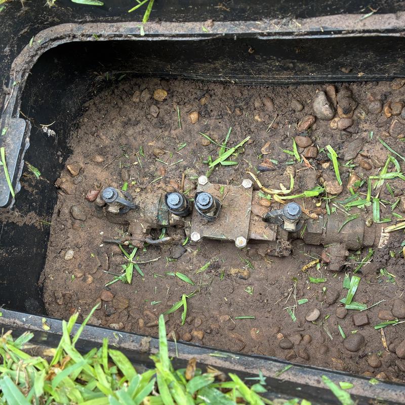 Sprinkler valve assembly in ground box with dirt and grass