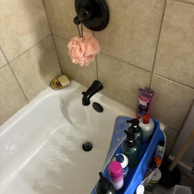 Bathtub faucet drain flowing with personal care items nearby Bathtub faucet drain flowing with personal care items nearby