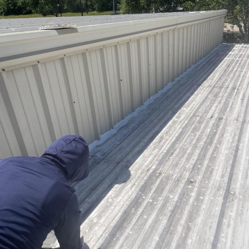 Metal roof panel seam sealing on commercial building