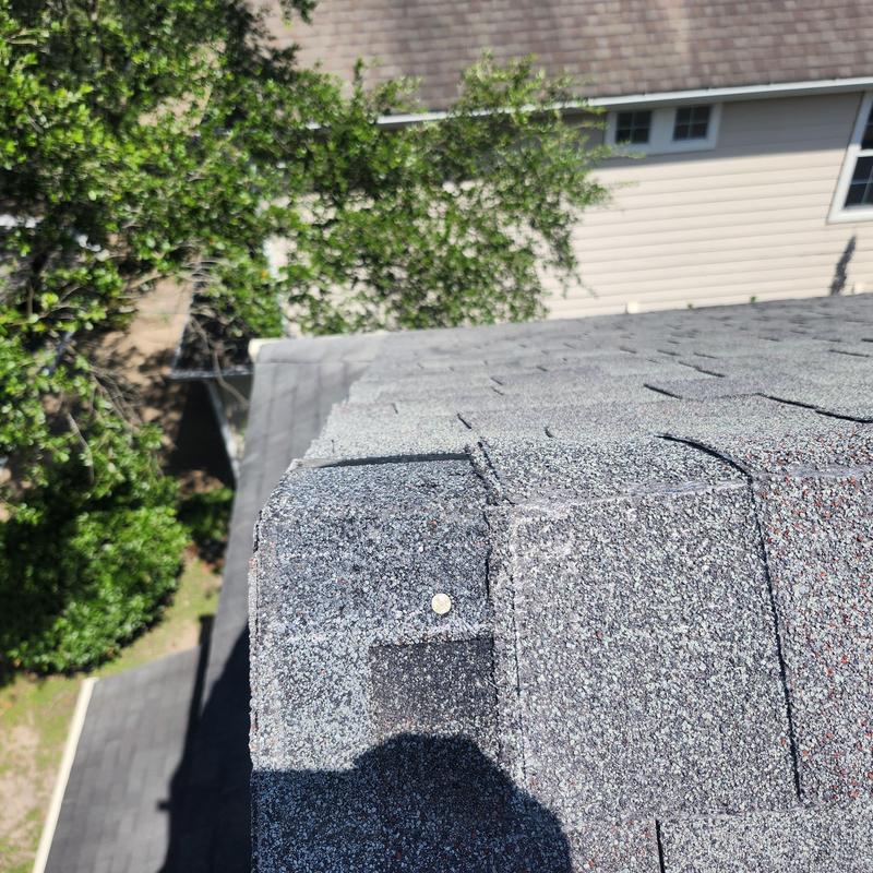 Pewter gray ridge shingle with exposed nail pop Pewter gray ridge shingle with exposed nail pop