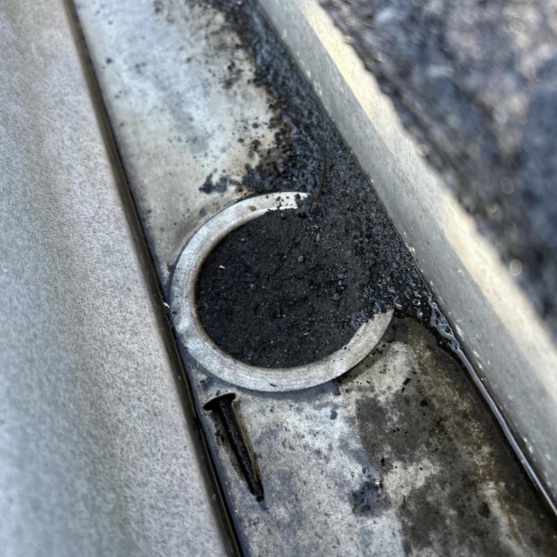 Roof gutter with granule buildup and exposed fastener