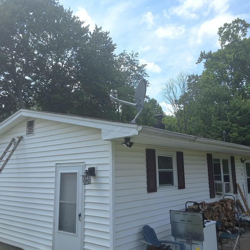 Satellite dish on house roof with white siding Satellite dish on house roof with white siding
