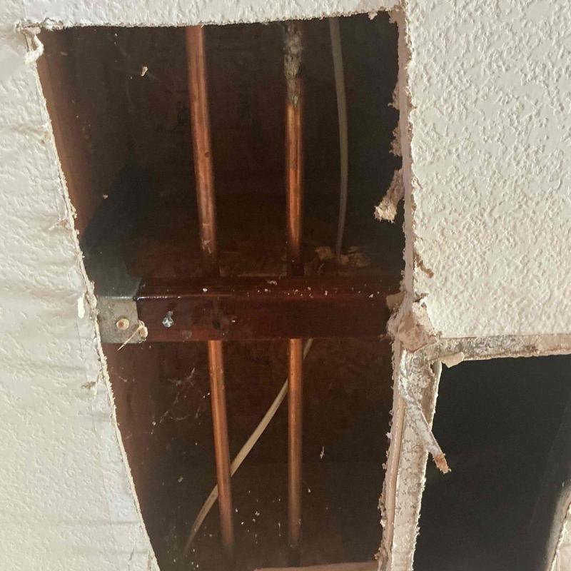 Copper plumbing pipes inside wall cavity with drywall removed