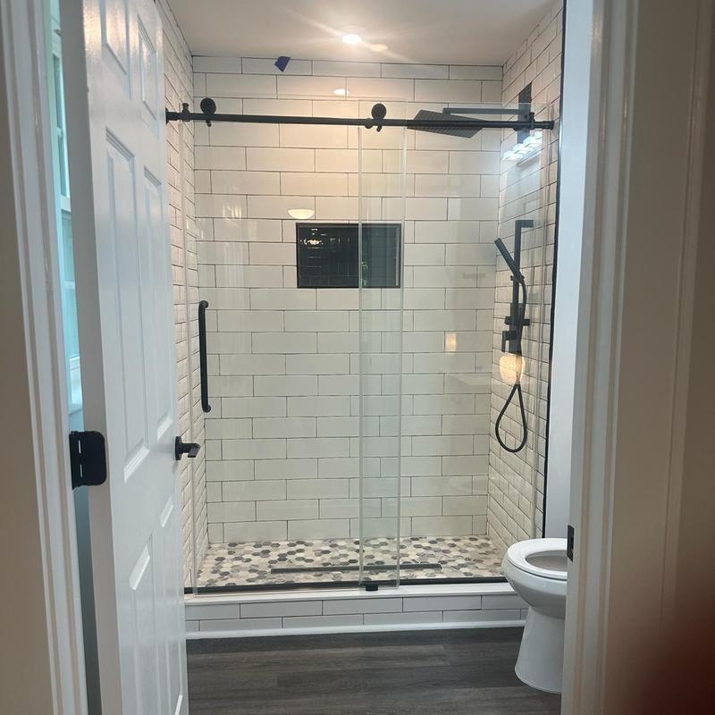 Glass shower enclosure with black fixtures and tiled walls Glass shower enclosure with black fixtures and tiled walls