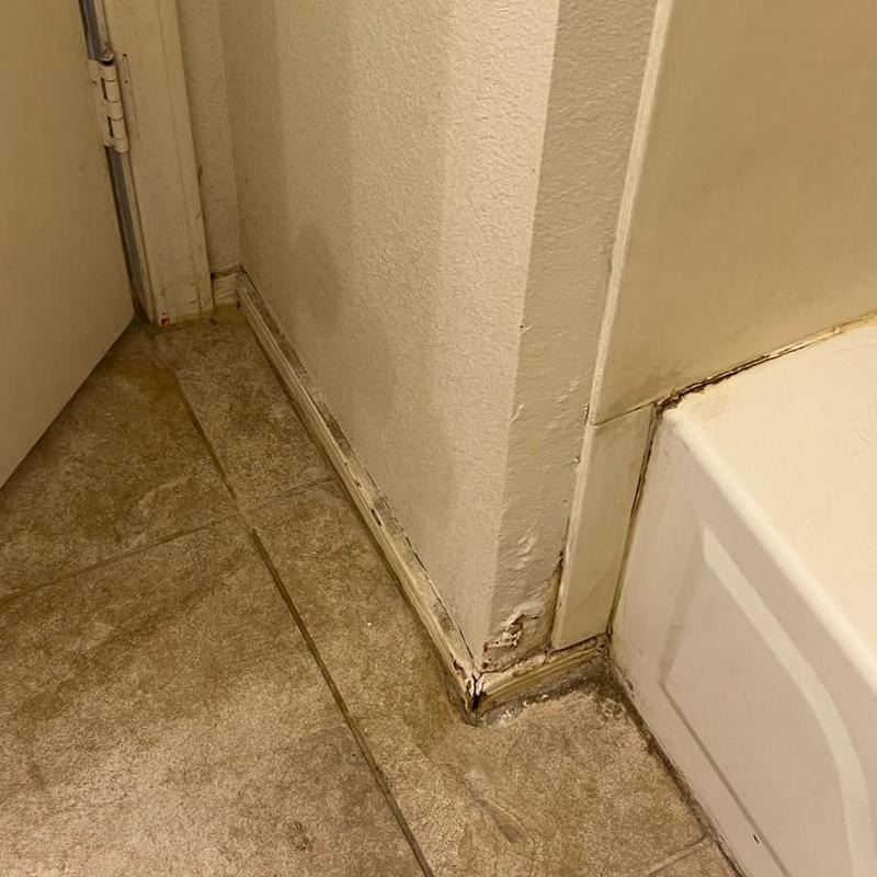 Bathroom floor water damage near tub and wall baseboard Bathroom floor water damage near tub and wall baseboard