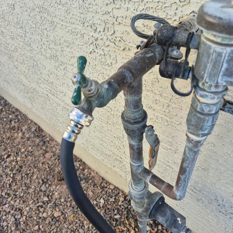 Outdoor hose bib with attached garden hose and plumbing pipes
