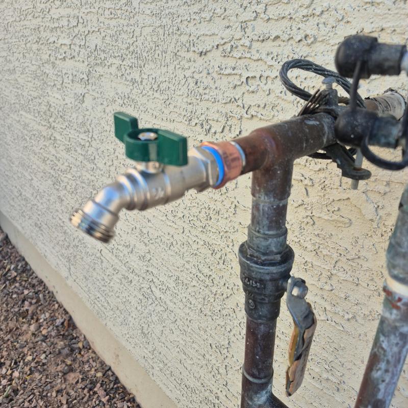 Outdoor hose bib with green handle on copper pipe