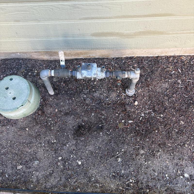Irrigation valve box and piping by house exterior wall Irrigation valve box and piping by house exterior wall