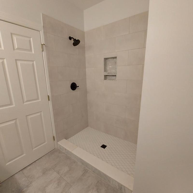 Shower tile walls and floor with niche and black fixtures Shower tile walls and floor with niche and black fixtures