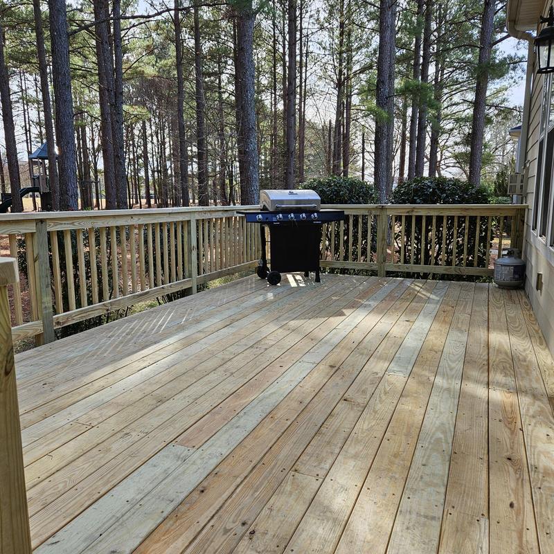 Wood deck with railing and gas grill in backyard Wood deck with railing and gas grill in backyard