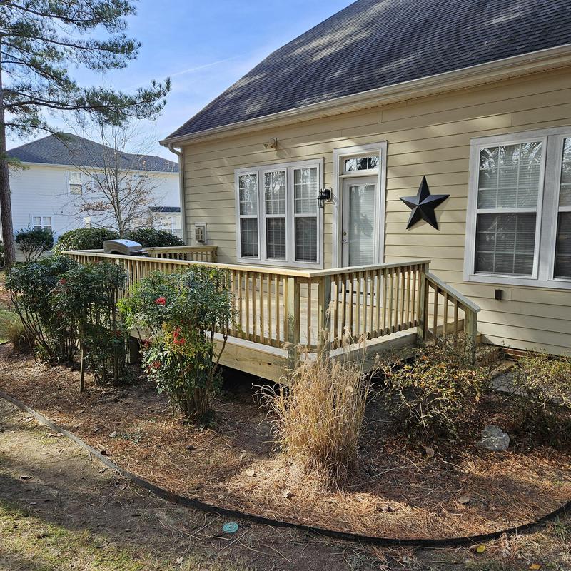 Wood deck with railing and newel posts in backyard Wood deck with railing and newel posts in backyard