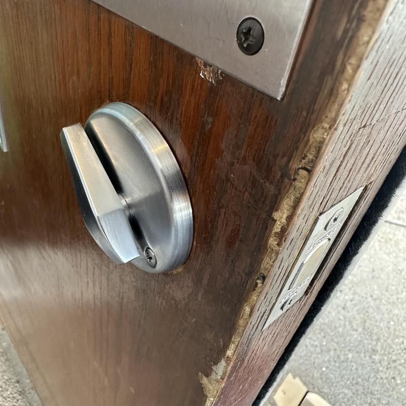 Deadbolt lock on wooden door with metal strike plate