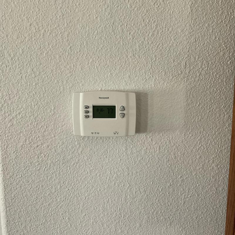 Digital thermostat on textured wall display 77°F Digital thermostat on textured wall display 77°F