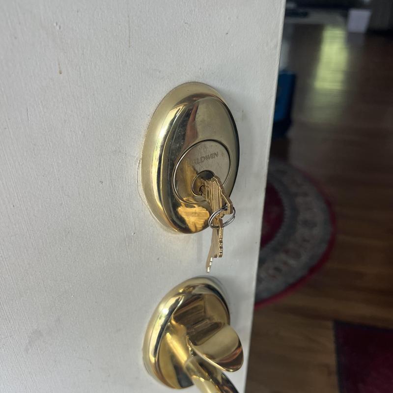 Front door lock with keys inserted on white door