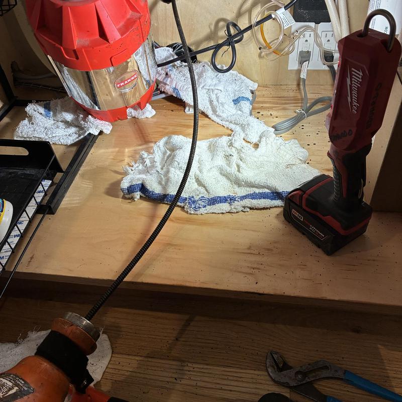 Kitchen drain line cable with tools under sink