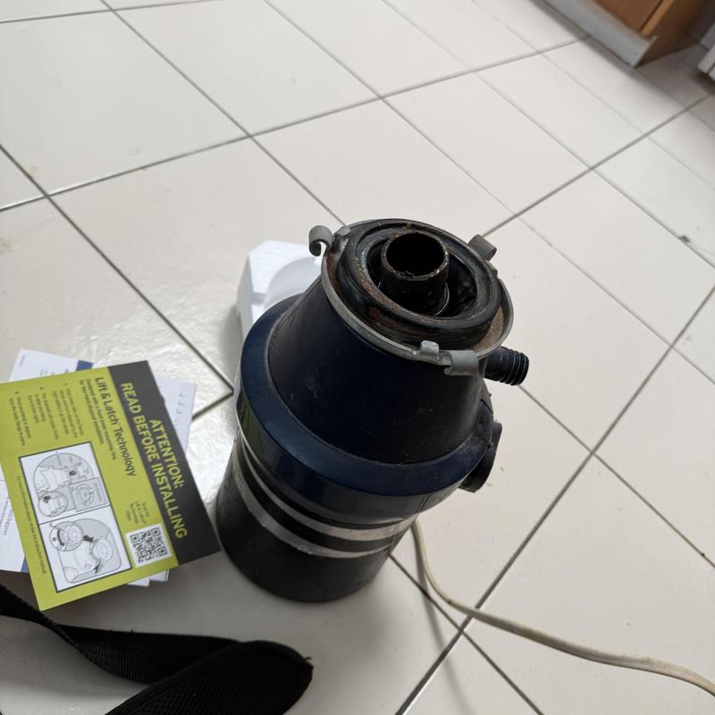 Garbage disposal unit on tiled floor with instructions