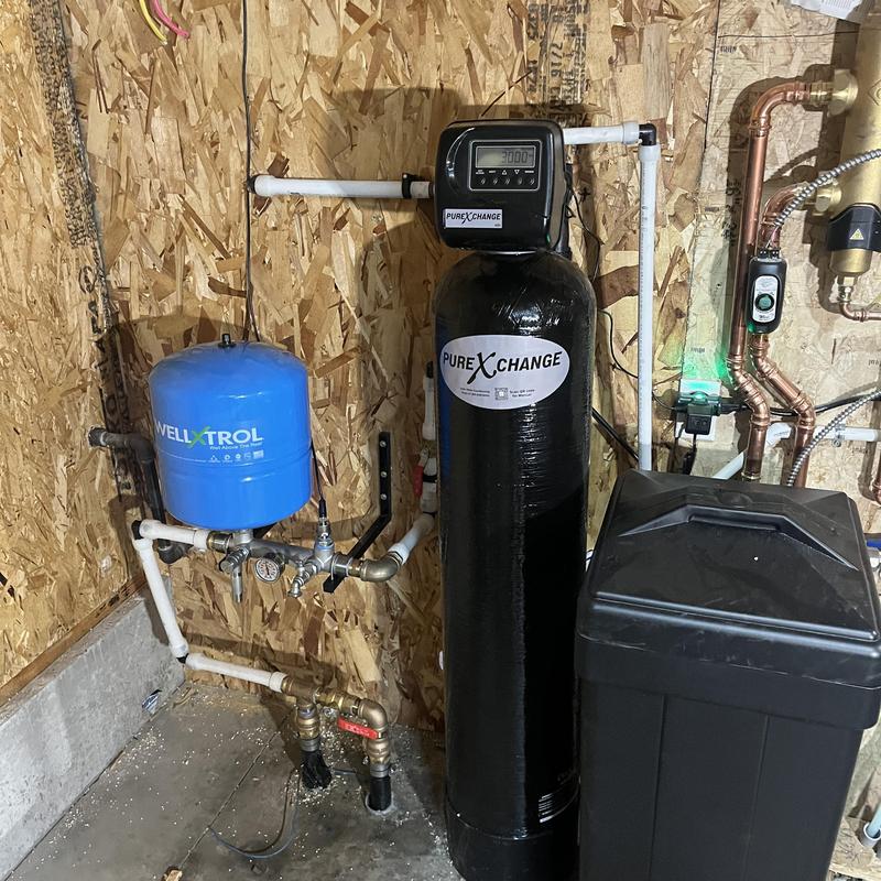 Water softener system with pressure tank and piping in basement
