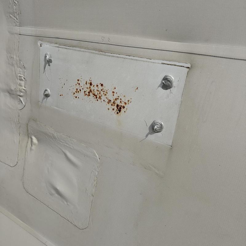 Roof membrane patch with rust and sealant spots