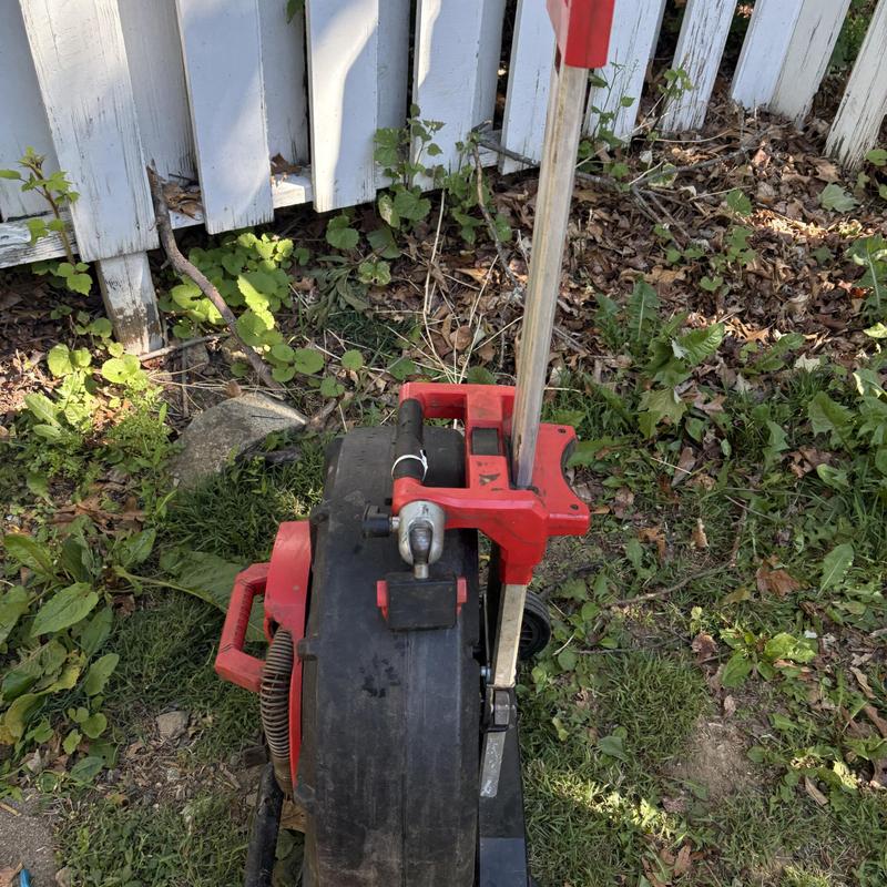 Drain cleaning jet machine on grass near fence Drain cleaning jet machine on grass near fence