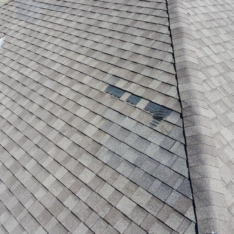 Asphalt shingles with wind damage on a roof ridge